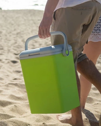 A traveler carrying a portable cooler near a vehicle