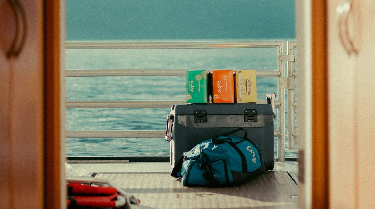 A traveler arranging luggage and a portable cooler at an open vehicle